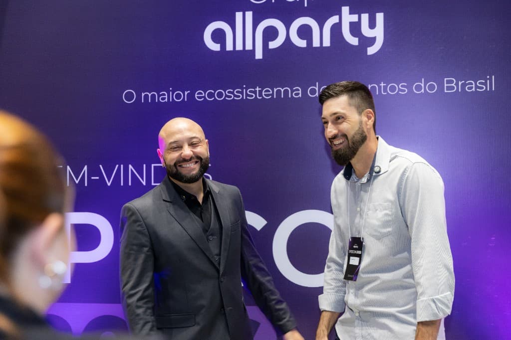 Caio Basílio recebendo um convidado no painel de boas-vindas do IPDCON 2026